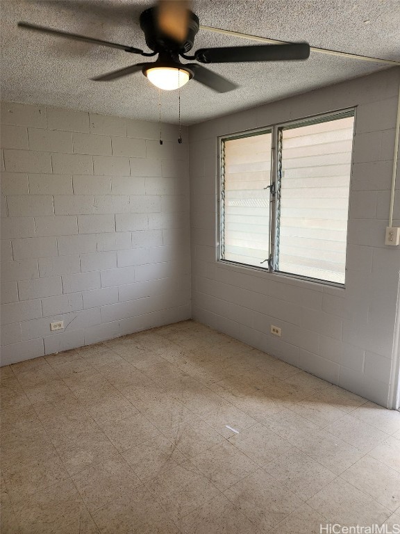 empty room with ceiling fan and a textured ceiling