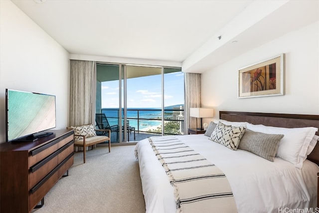 carpeted bedroom featuring expansive windows, access to exterior, and a water view