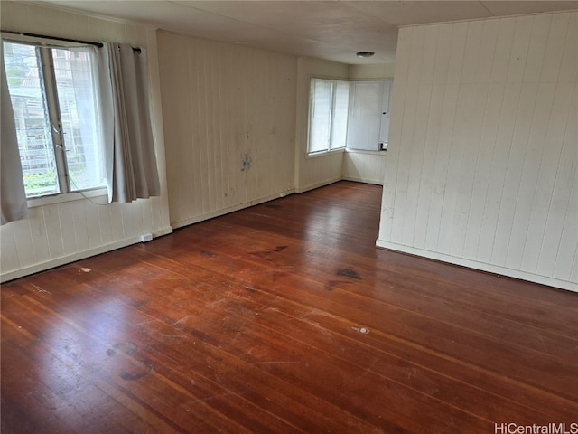 spare room featuring dark hardwood / wood-style flooring and wooden walls