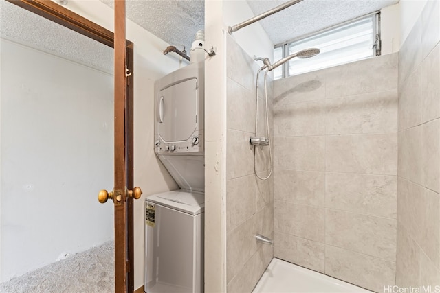 bathroom with stacked washer / drying machine, a tile shower, and a textured ceiling