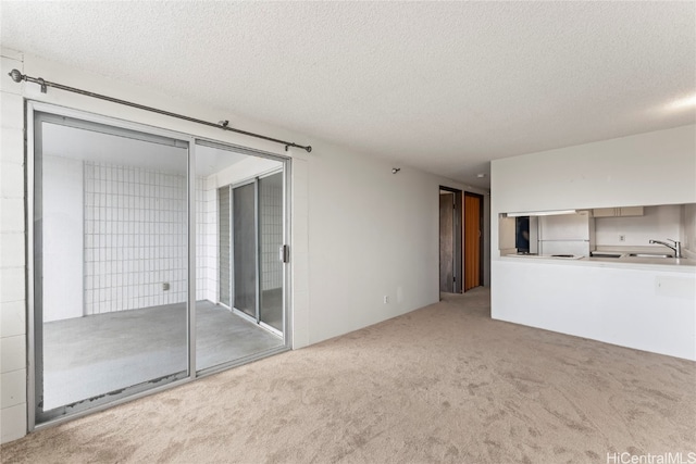 unfurnished living room featuring carpet, a textured ceiling, and sink