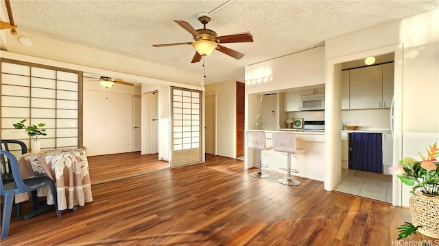 interior space featuring kitchen peninsula, a textured ceiling, dark hardwood / wood-style flooring, and ceiling fan