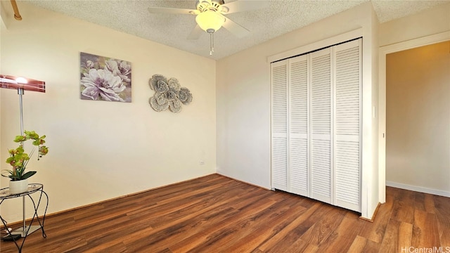 unfurnished bedroom featuring ceiling fan, dark hardwood / wood-style flooring, a textured ceiling, and a closet