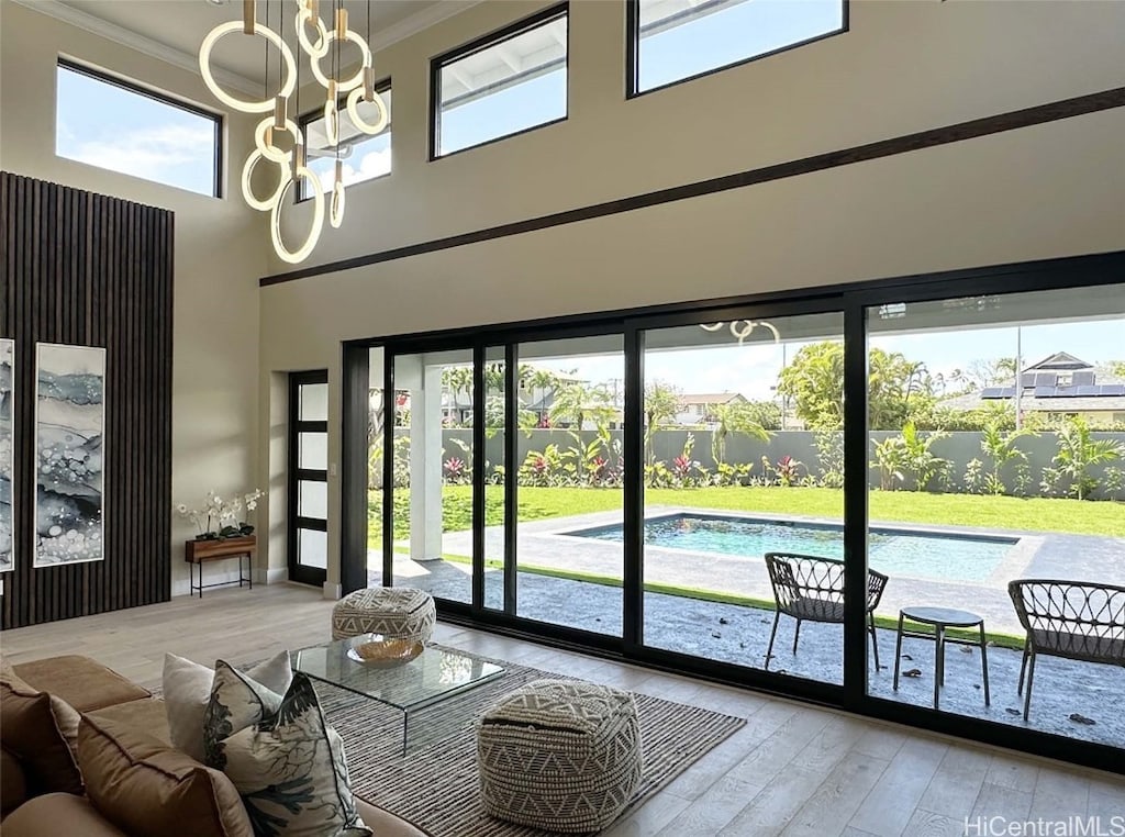 interior space featuring a wealth of natural light, light hardwood / wood-style flooring, a high ceiling, and ornamental molding