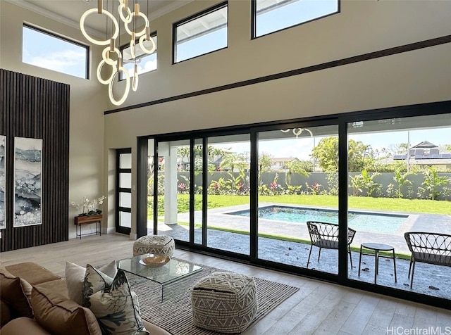 interior space featuring a wealth of natural light, light hardwood / wood-style flooring, a high ceiling, and ornamental molding