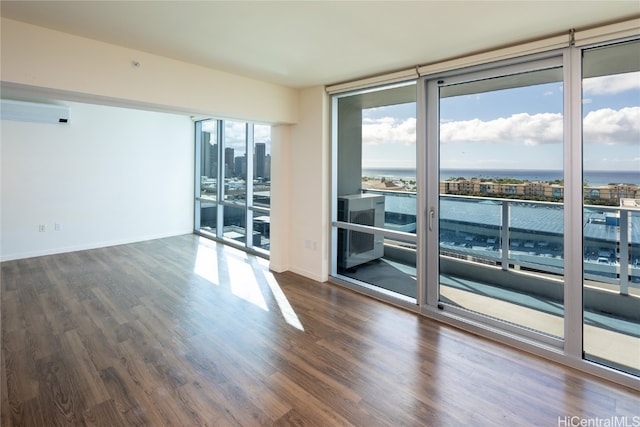 spare room featuring a wall unit AC, dark hardwood / wood-style flooring, a wall of windows, and a water view