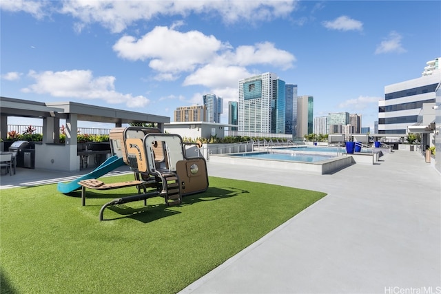 view of playground with a community pool and a lawn