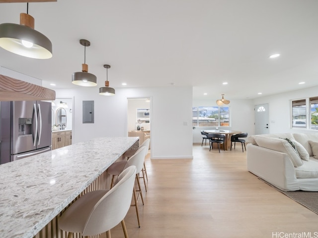 kitchen with plenty of natural light, light wood-type flooring, stainless steel refrigerator with ice dispenser, and hanging light fixtures