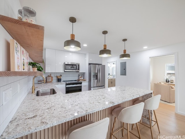 kitchen with sink, light hardwood / wood-style flooring, tasteful backsplash, white cabinetry, and stainless steel appliances