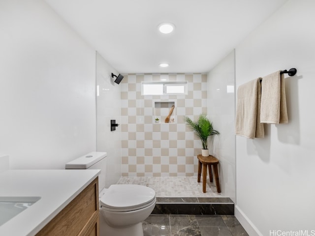 bathroom with vanity, toilet, and a tile shower