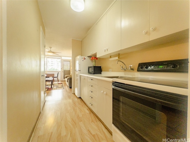 kitchen featuring sink, light hardwood / wood-style flooring, white refrigerator, range with electric stovetop, and white cabinets