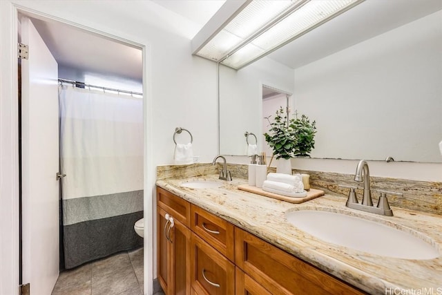 full bath with toilet, double vanity, a sink, and tile patterned floors