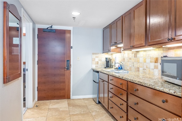 kitchen featuring light stone countertops, sink, decorative backsplash, light tile patterned floors, and appliances with stainless steel finishes