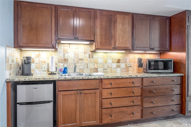 kitchen featuring backsplash, light stone counters, stainless steel appliances, sink, and light tile patterned flooring