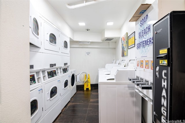 laundry room featuring washer and dryer, dark tile patterned flooring, and stacked washer and clothes dryer