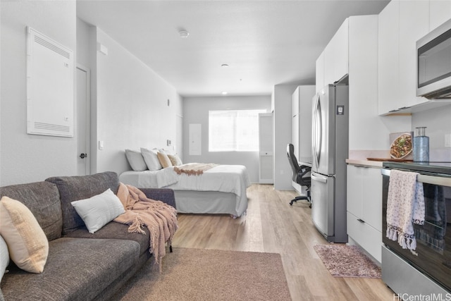 bedroom featuring light hardwood / wood-style flooring and stainless steel refrigerator