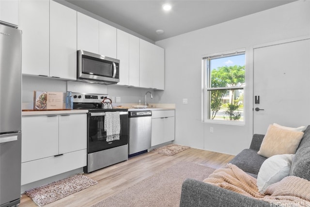 kitchen featuring white cabinets, sink, light wood-type flooring, and stainless steel appliances