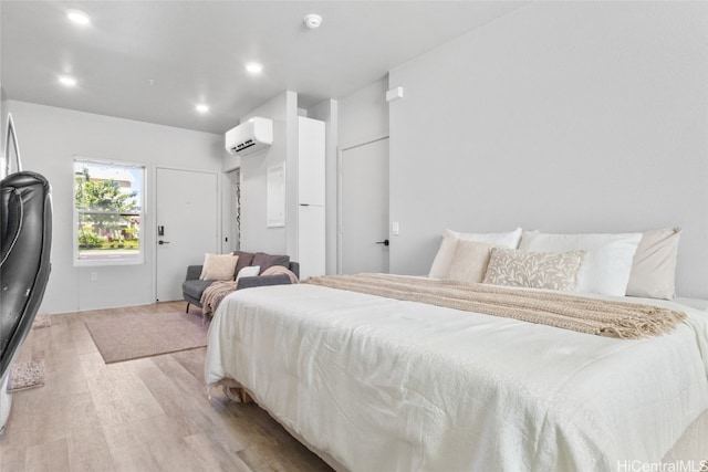 bedroom featuring a wall mounted air conditioner and light wood-type flooring