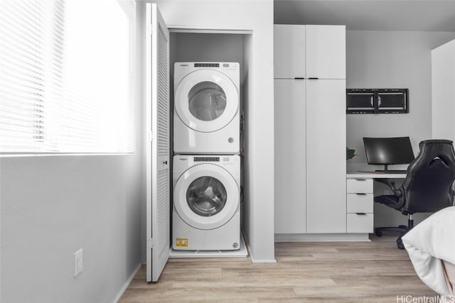 laundry area with light hardwood / wood-style floors and stacked washer / dryer