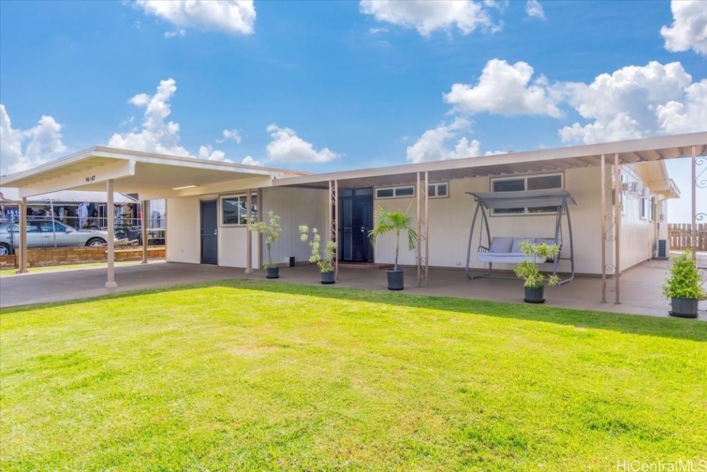 back of house featuring a carport and a lawn