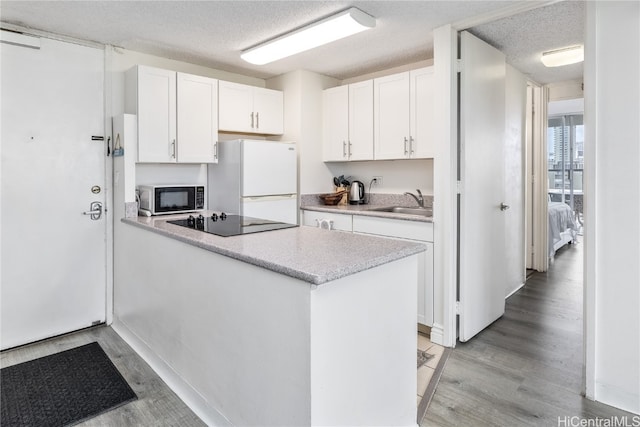 kitchen with white cabinetry, black appliances, a textured ceiling, and light hardwood / wood-style floors