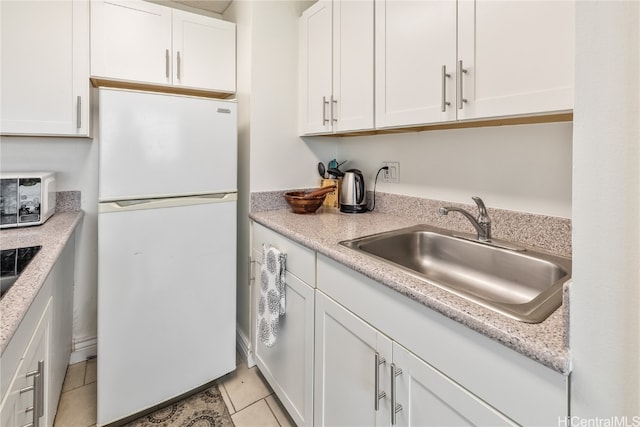 kitchen with white cabinets, white fridge, light tile patterned flooring, and sink