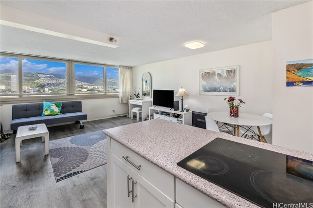 kitchen featuring white cabinets, a textured ceiling, black cooktop, and light hardwood / wood-style flooring