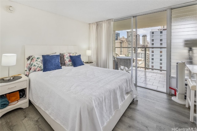 bedroom with expansive windows and hardwood / wood-style flooring