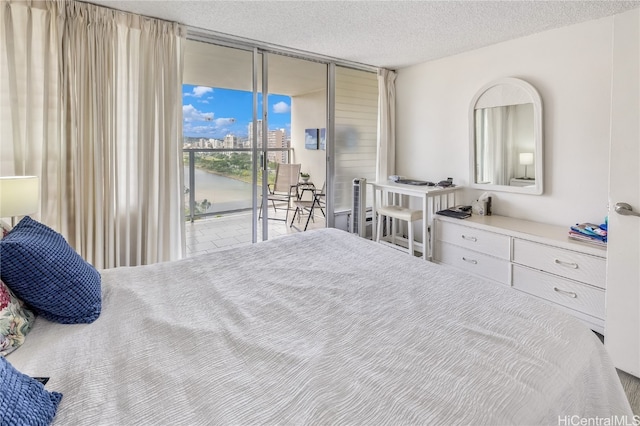 bedroom with access to outside, floor to ceiling windows, and a textured ceiling