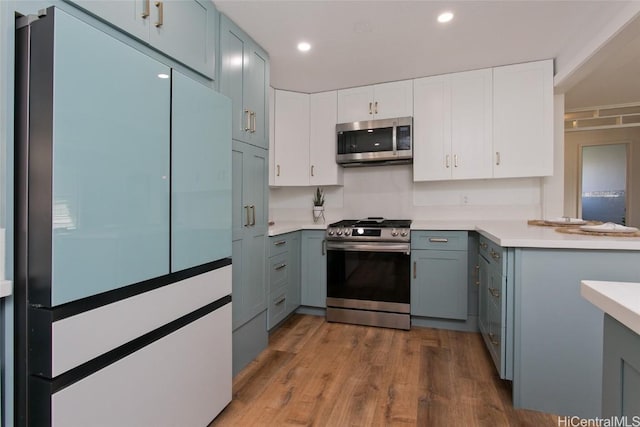 kitchen featuring gray cabinets, white cabinets, light wood-type flooring, and appliances with stainless steel finishes