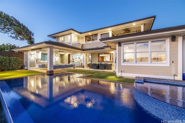 back house at dusk featuring a pool with hot tub, ceiling fan, and an outdoor hangout area