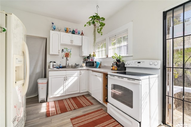 kitchen with white cabinetry, white appliances, sink, and light hardwood / wood-style flooring