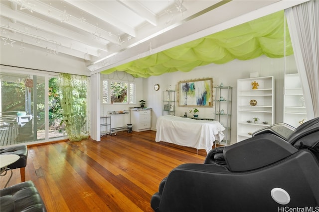 bedroom with beam ceiling, hardwood / wood-style floors, and access to outside