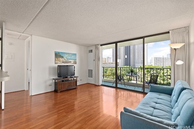 living room with hardwood / wood-style floors, a textured ceiling, and a wall of windows