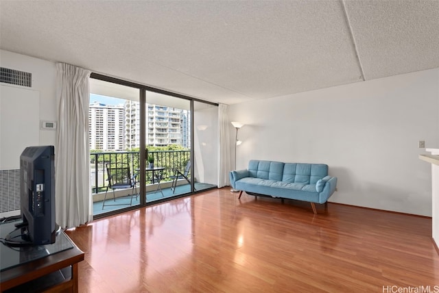 living room with wood-type flooring, a textured ceiling, and floor to ceiling windows