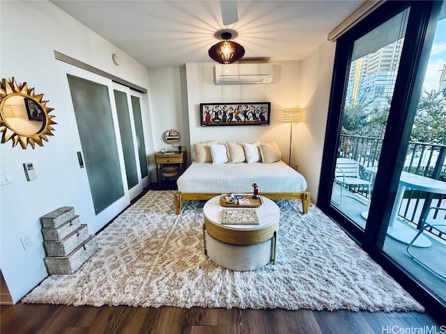 bedroom with access to outside, wood-type flooring, and an AC wall unit