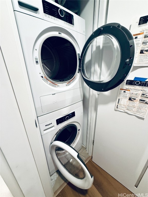 laundry area featuring stacked washing maching and dryer and hardwood / wood-style flooring