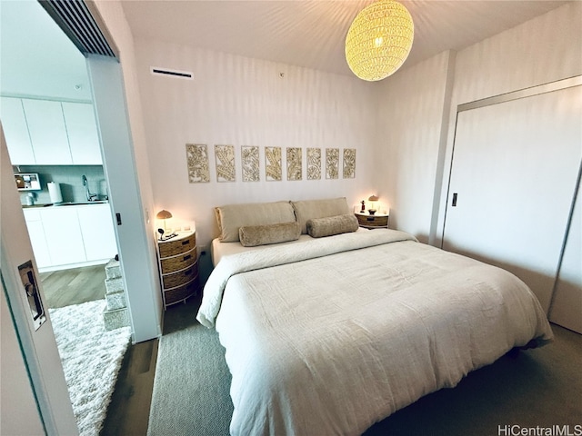 bedroom with a closet, sink, and dark wood-type flooring