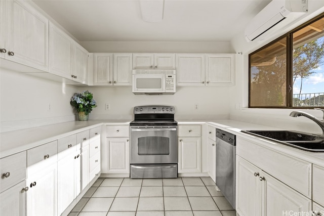 kitchen featuring sink, light tile patterned flooring, a wall unit AC, white cabinets, and appliances with stainless steel finishes