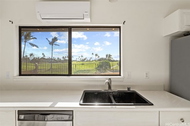 kitchen featuring an AC wall unit, white cabinetry, sink, and stainless steel dishwasher