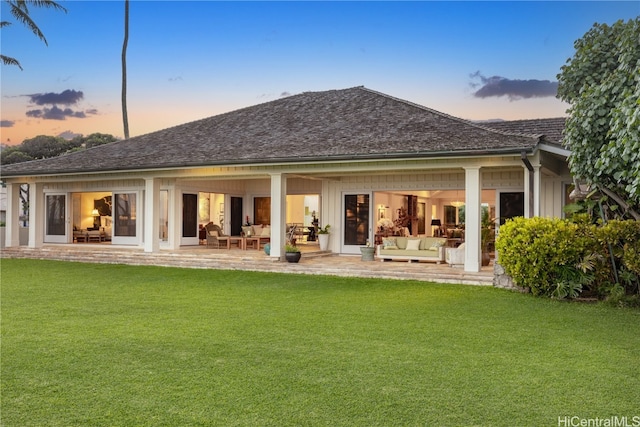 back house at dusk with a yard, an outdoor hangout area, and a patio area