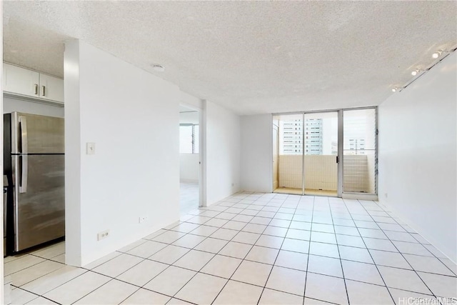 tiled empty room with plenty of natural light and a textured ceiling