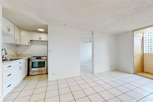 kitchen featuring white cabinets, a textured ceiling, sink, and stainless steel range oven