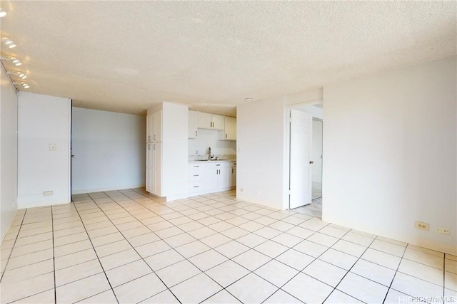 interior space with light tile patterned flooring, a textured ceiling, and sink