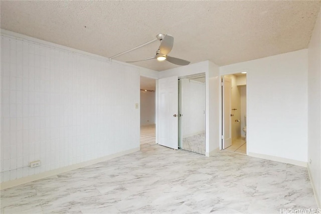 unfurnished bedroom with ceiling fan, ensuite bath, a textured ceiling, and a closet