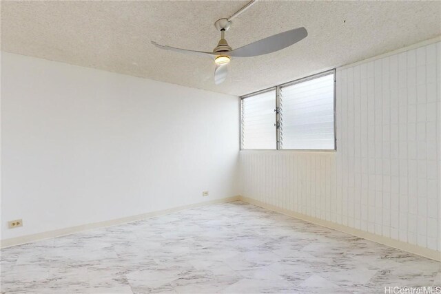 empty room with ceiling fan and a textured ceiling