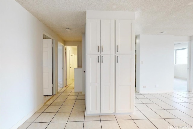 hallway featuring light tile patterned floors and a textured ceiling