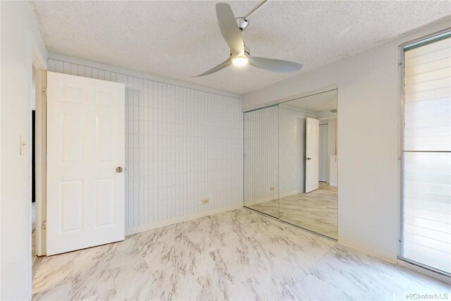 unfurnished bedroom featuring a textured ceiling, a closet, and ceiling fan