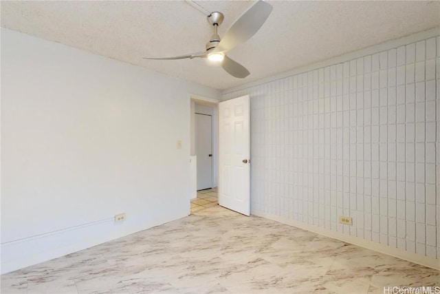 empty room with ceiling fan and a textured ceiling