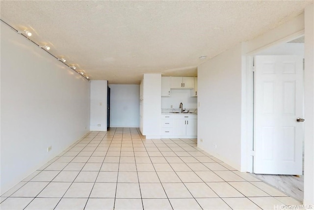 unfurnished living room featuring sink, light tile patterned floors, and a textured ceiling